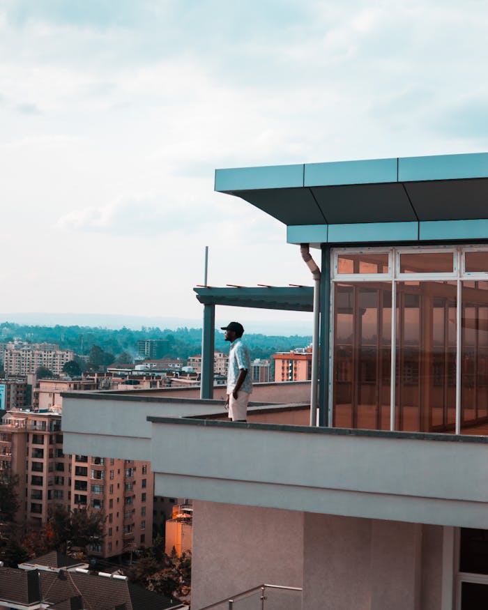 services-04 Man standing on a modern balcony overlooking a city skyline on a bright day.